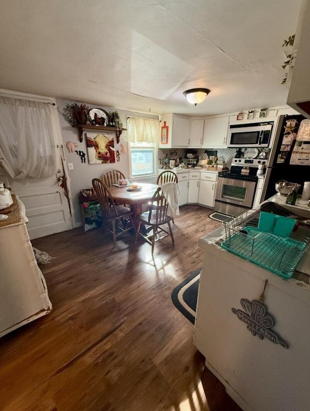 kitchen featuring dark hardwood / wood-style flooring, tasteful backsplash, white cabinets, and appliances with stainless steel finishes