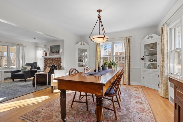 dining room with a fireplace, radiator heating unit, and light wood-type flooring