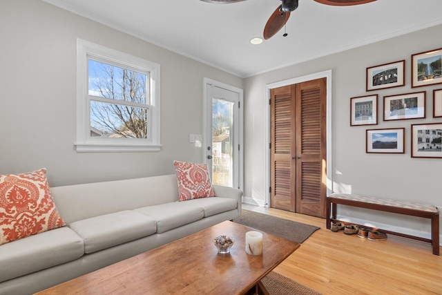 living room featuring hardwood / wood-style flooring, ornamental molding, and ceiling fan