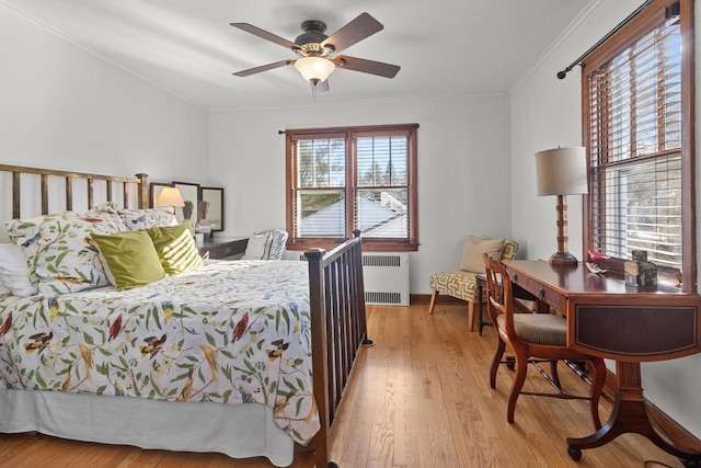 bedroom with crown molding, ceiling fan, radiator heating unit, and light hardwood / wood-style flooring