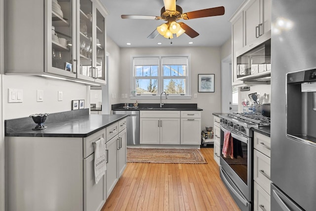 kitchen featuring white cabinetry, sink, ceiling fan, stainless steel appliances, and light hardwood / wood-style flooring