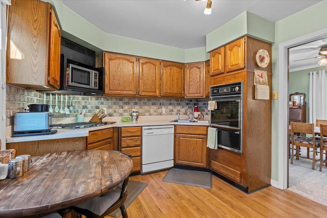 kitchen featuring stainless steel appliances, tasteful backsplash, sink, and light hardwood / wood-style flooring