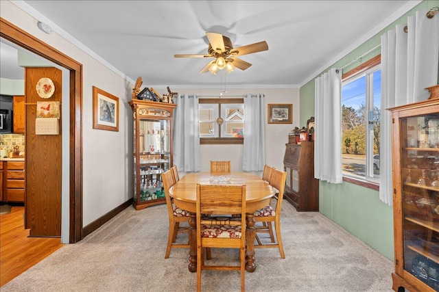 carpeted dining area with crown molding and ceiling fan