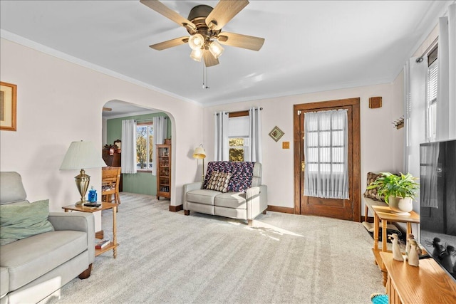 carpeted living room featuring a wealth of natural light, ornamental molding, and ceiling fan