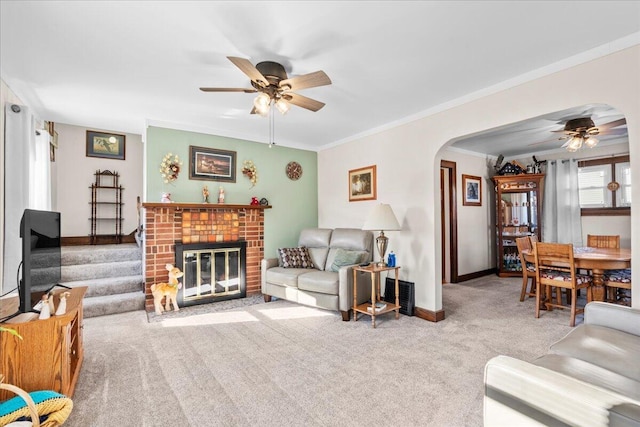 carpeted living room with crown molding, a fireplace, and ceiling fan