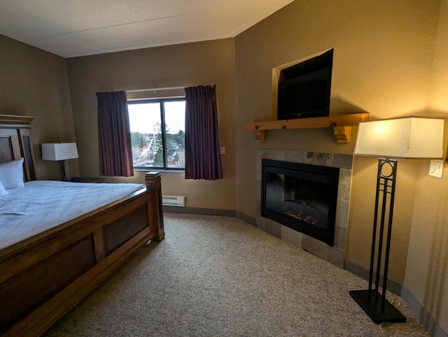 bedroom featuring a tile fireplace, carpet, and a baseboard heating unit