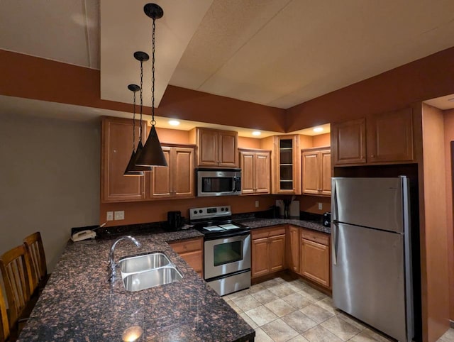 kitchen featuring stainless steel appliances, sink, dark stone countertops, and decorative light fixtures