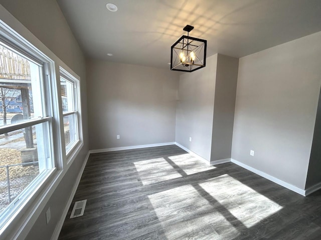 unfurnished dining area featuring a notable chandelier and dark hardwood / wood-style flooring