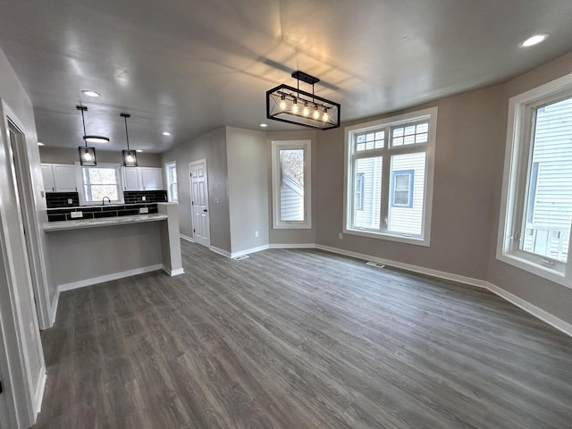 kitchen with white cabinetry, dark hardwood / wood-style flooring, tasteful backsplash, and pendant lighting