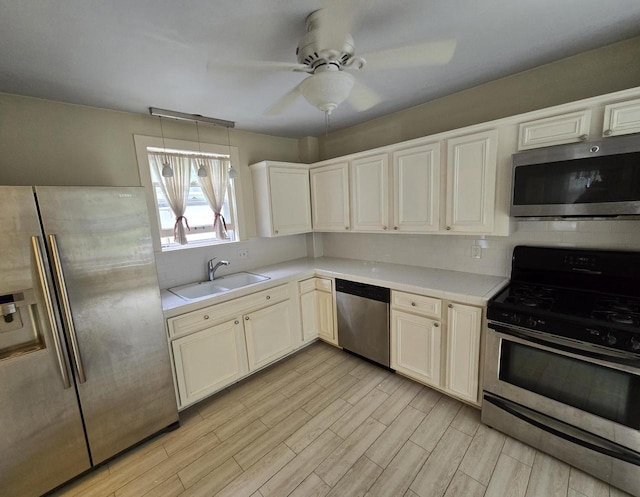 kitchen with sink, appliances with stainless steel finishes, ceiling fan, light hardwood / wood-style floors, and decorative backsplash