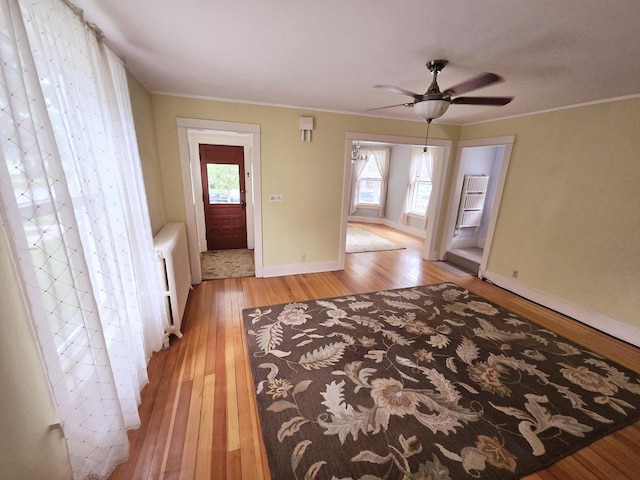 entrance foyer featuring radiator, ornamental molding, ceiling fan, and light wood-type flooring