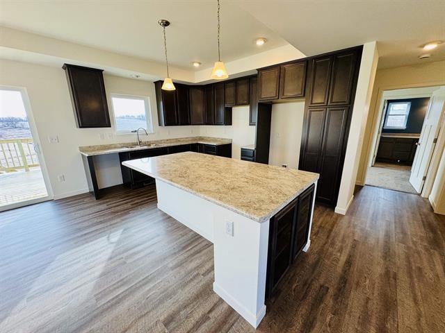 kitchen featuring hanging light fixtures, a kitchen island, dark wood-type flooring, and dark brown cabinetry