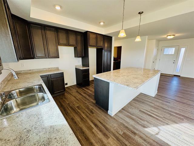 kitchen featuring sink, dark hardwood / wood-style floors, hanging light fixtures, and a center island