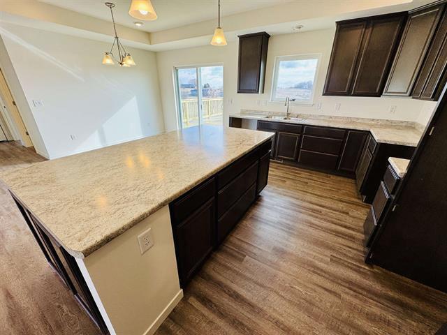 kitchen with a kitchen island, sink, dark hardwood / wood-style flooring, and decorative light fixtures