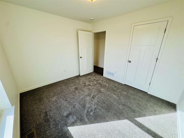 unfurnished bedroom with dark carpet