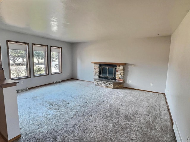 unfurnished living room with a stone fireplace and carpet flooring