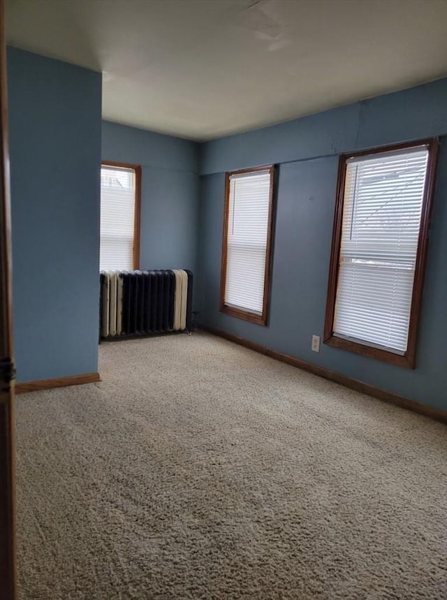 carpeted empty room featuring radiator heating unit