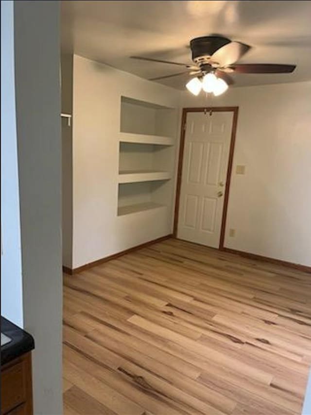 interior space with built in features, ceiling fan, and light wood-type flooring