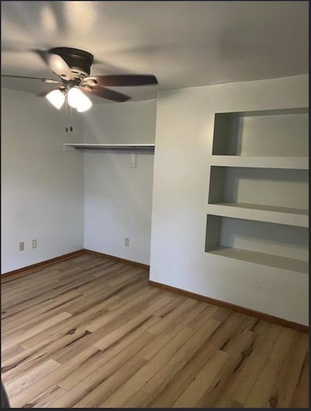 spare room with hardwood / wood-style floors, built in features, and ceiling fan