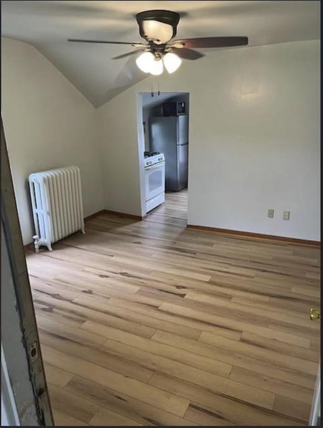 interior space with ceiling fan, lofted ceiling, radiator, and light hardwood / wood-style floors