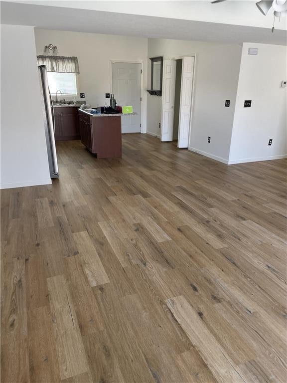 unfurnished living room featuring sink, dark wood-type flooring, and ceiling fan