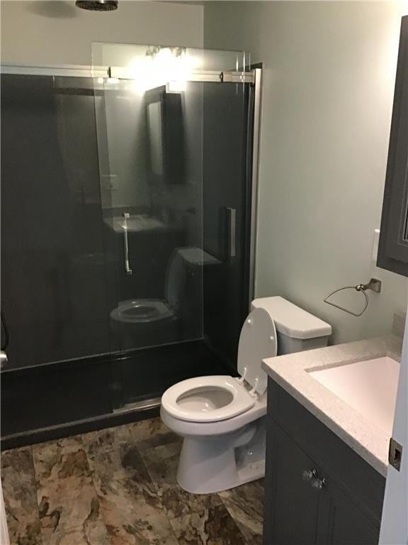 bathroom featuring vanity, an enclosed shower, and toilet