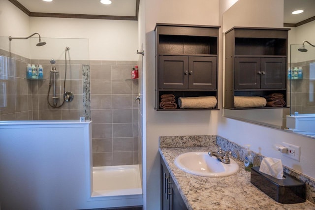 bathroom with vanity, ornamental molding, and tiled shower