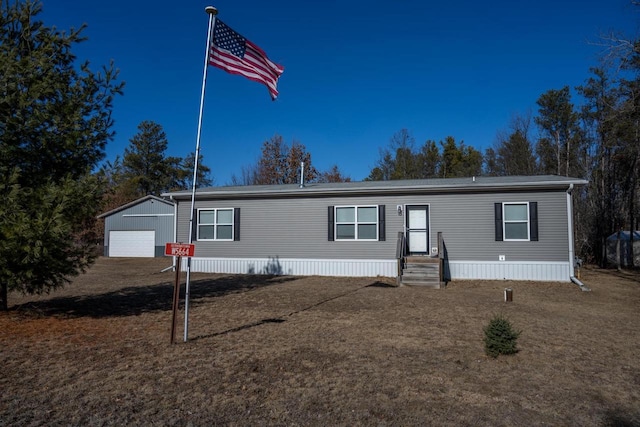 manufactured / mobile home with a garage, an outbuilding, and a front yard