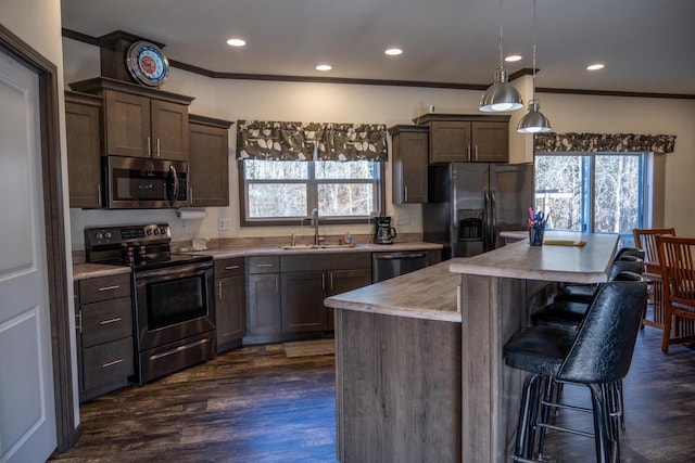 kitchen with sink, a center island, hanging light fixtures, ornamental molding, and appliances with stainless steel finishes