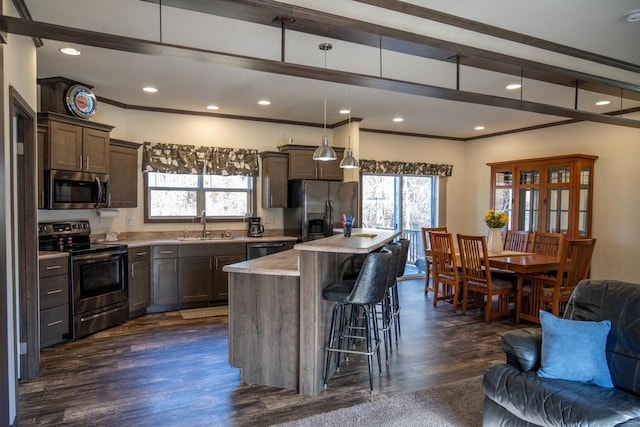 kitchen with sink, hanging light fixtures, stainless steel appliances, a healthy amount of sunlight, and a kitchen island