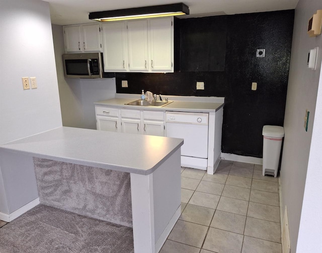 kitchen with light tile patterned flooring, sink, white cabinets, white dishwasher, and kitchen peninsula