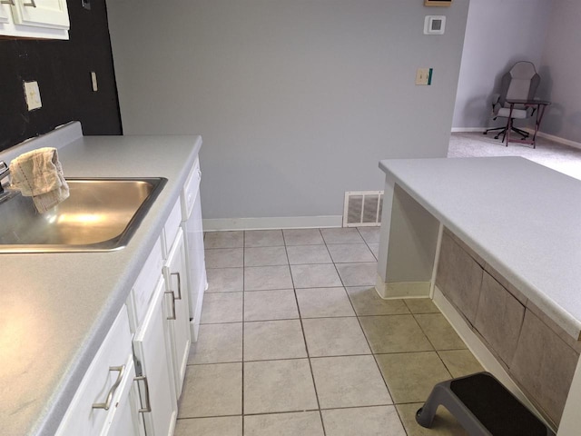 kitchen with white cabinetry, sink, and light tile patterned floors