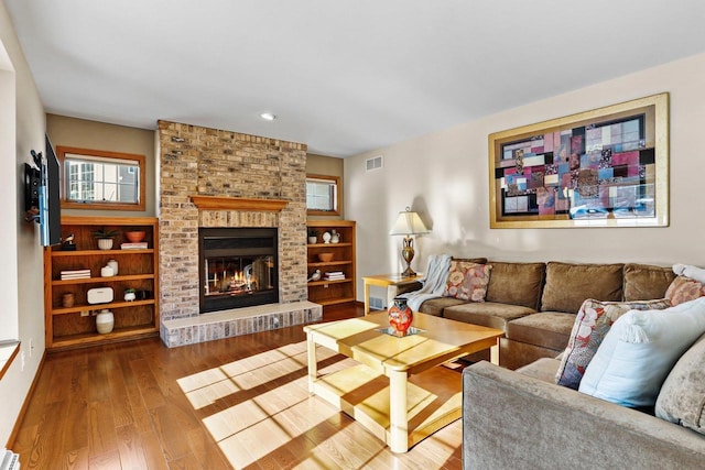 living room featuring a brick fireplace and light hardwood / wood-style flooring