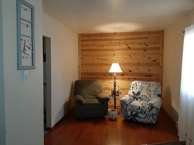 sitting room featuring hardwood / wood-style flooring and wooden walls