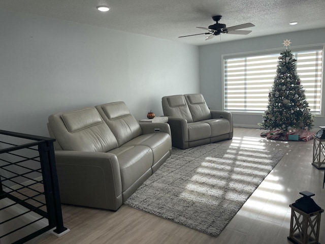 living room with ceiling fan, a textured ceiling, light hardwood / wood-style flooring, and a wealth of natural light