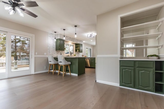 kitchen with hanging light fixtures, a breakfast bar area, kitchen peninsula, and green cabinets