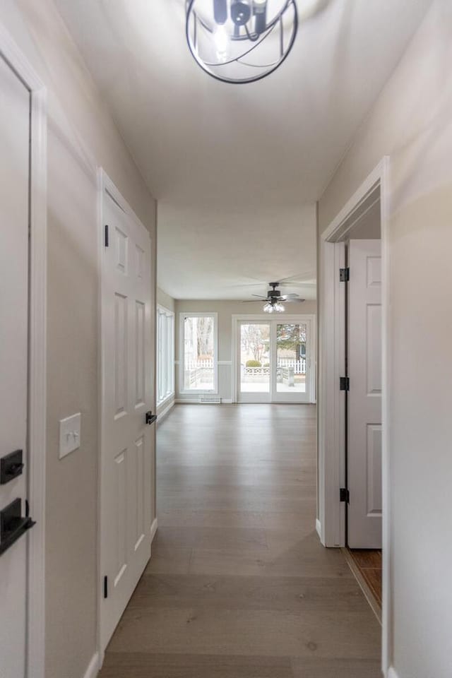 corridor with an inviting chandelier and light hardwood / wood-style floors