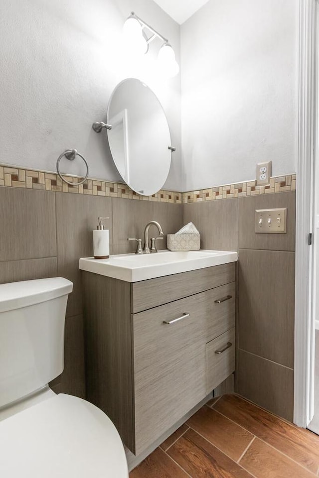 bathroom with vanity, tile walls, and toilet