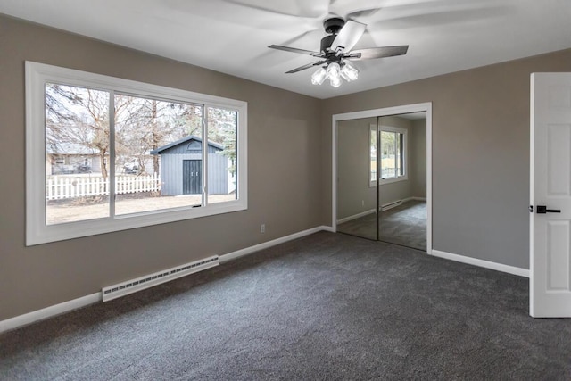 unfurnished bedroom with a baseboard radiator, a closet, ceiling fan, and dark colored carpet