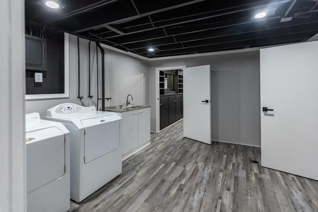 laundry room featuring cabinets, wood-type flooring, washer and clothes dryer, and sink