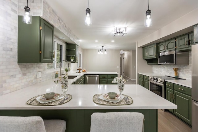 kitchen featuring green cabinetry, appliances with stainless steel finishes, a kitchen breakfast bar, and kitchen peninsula