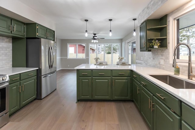 kitchen featuring appliances with stainless steel finishes, sink, green cabinets, and decorative light fixtures