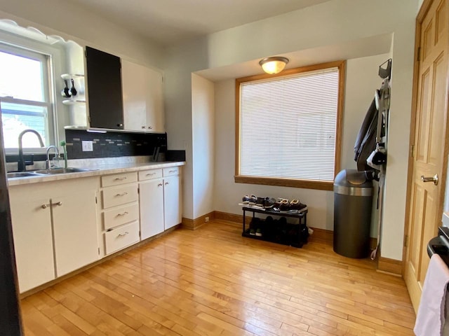 kitchen featuring sink, backsplash, white cabinets, and light wood-type flooring