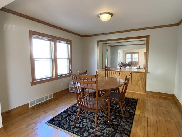 dining space with hardwood / wood-style flooring and ornamental molding