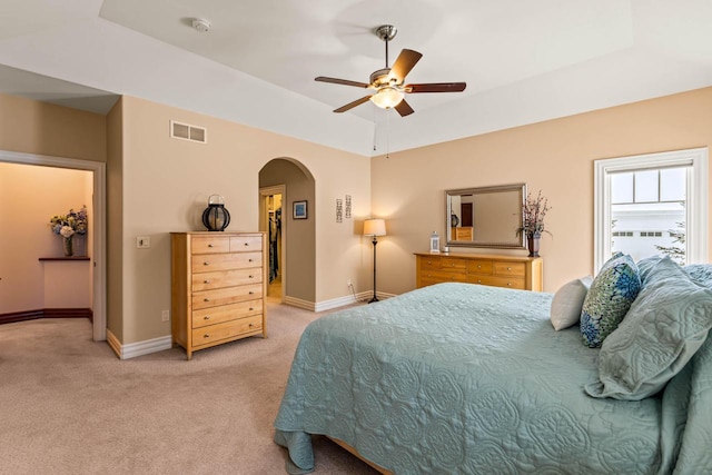 carpeted bedroom featuring a tray ceiling and ceiling fan