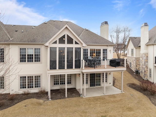 rear view of house with cooling unit, a yard, a sunroom, and a patio