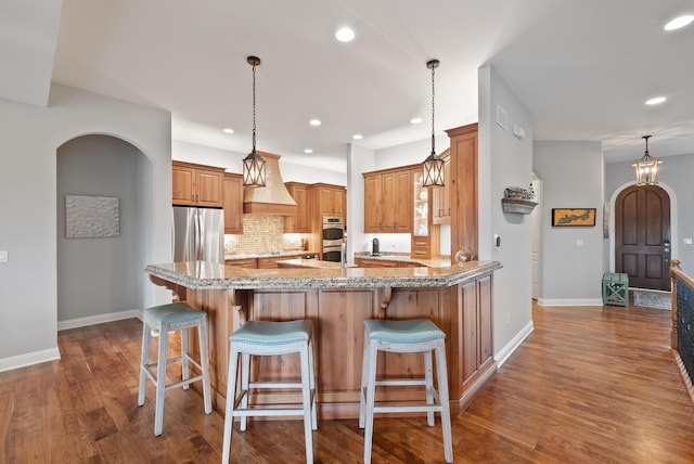 kitchen with hanging light fixtures, light stone countertops, appliances with stainless steel finishes, and a breakfast bar area