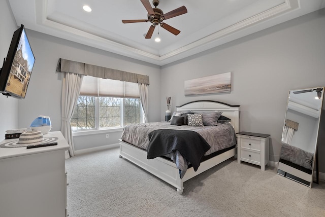 bedroom with light carpet, a tray ceiling, ornamental molding, and ceiling fan