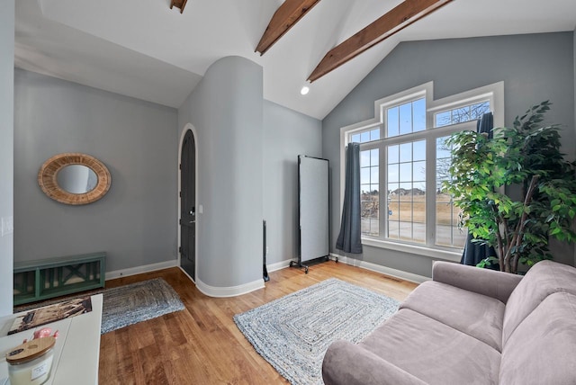 living room featuring light hardwood / wood-style flooring and vaulted ceiling with beams