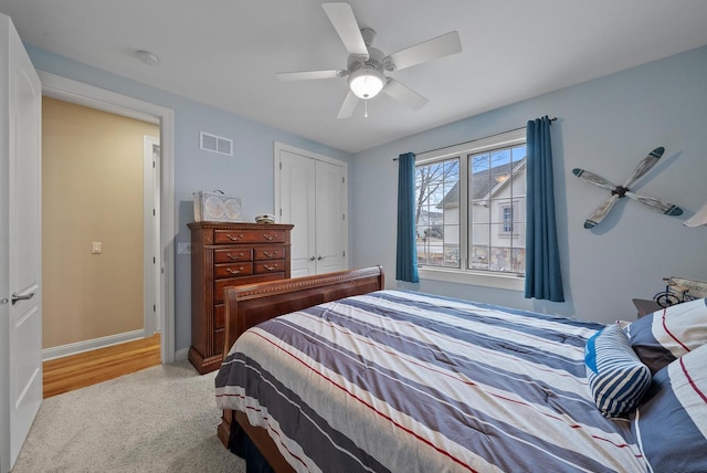 bedroom featuring light carpet, ceiling fan, and a closet